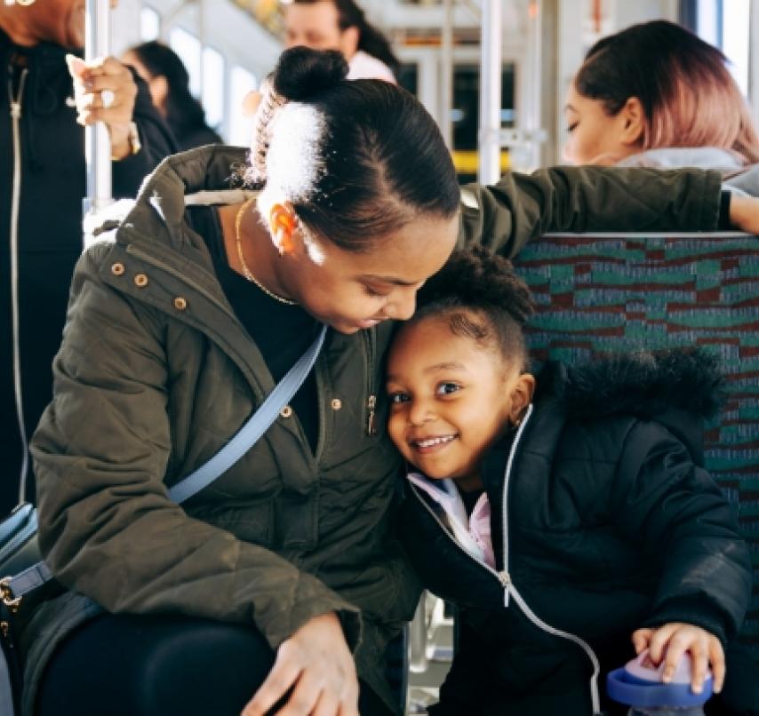 A woman and a child smile while aboard a Link light rail train.
