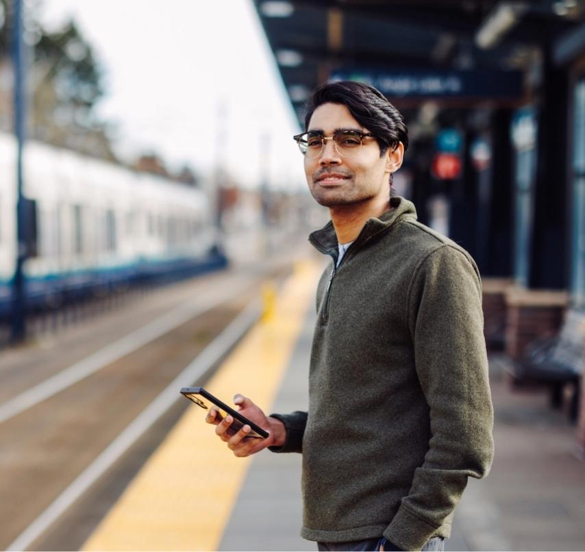 A passenger holding a phone at a Sounder station.