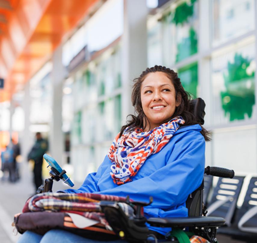 A rider in a wheelchair smiles at a light rail station.