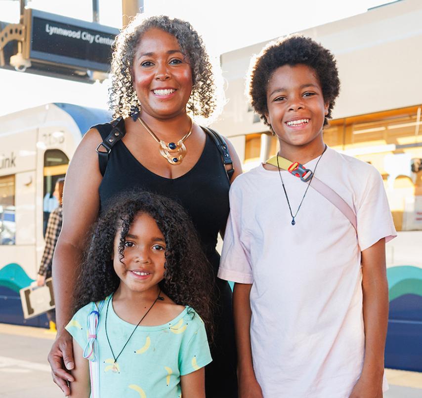 A family smiles at a light rail opening celebration.