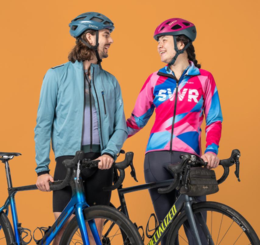 Two bike riders pose for a portrait with their bikes.