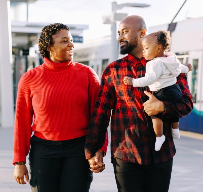 A family smiles at each other as they walk through a Link light rail station