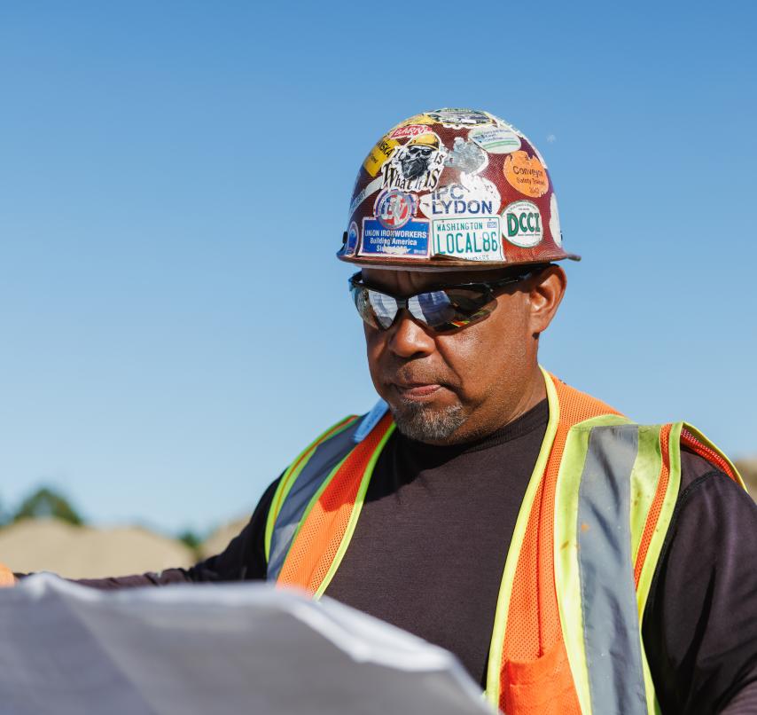 Person in hard hat reviewing construction plans